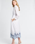 Woman wearing a white dress with blue lace details on a white background