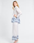 Woman wearing a white blouse with blue lace details on the trim on a white background