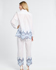 Woman wearing a white outfit with blue lace details on a white background