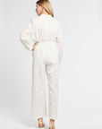Woman modeling a long sleeve white floral blouse and full length white floral pants against a white backdrop