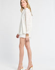 Woman modeling a long sleeve white floral blouse against a white background