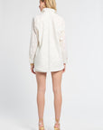 Woman modeling a long sleeve white floral blouse and the matching shorts on a white backdrop