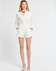 Woman modeling white floral shorts and a long sleeve blouse on a white backdrop