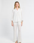 Woman wearing a white lace tunic on a white background with flats