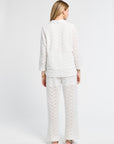 Lady modeling a white lace tunic and pants against a white background