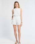 Woman modeling lace white shorts and a sleeveless blouse against a white backdrop