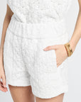 White lace shorts worn by a person on a light gray background