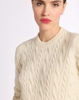 Close up of woman wearing a cashmere cream cable knit crew sweater on white background