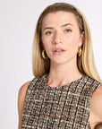 Headshot of woman in tan and black plaid tweed dress and gold earrings against a white background