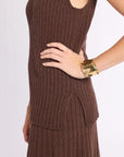 Close up of woman with hand on hip wearing brown ribbed sleeveless top and matching skirt on a white background