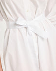 A close-up detail shot of the white cotton sash tied in a bow around the waist of the shirt dress.