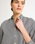 A woman wearing a black and white striped shirt with a collar and button-up front.