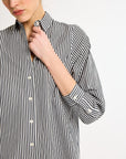 A woman wearing a black and white striped shirt with a collar and button-up front.