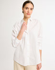 A woman wearing a white, long-sleeved, button-up shirt with a collar.