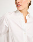 Close up of a woman wearing a white, button-up shirt with a collar.