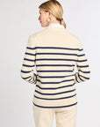 Woman wearing a cream and navy striped sweater with a plain background