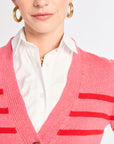 Person wearing a pink cardigan with red stripes over a white shirt.