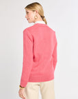 Woman wearing a pink sweater on a plain background