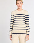Woman wearing a cream and navy striped sweater on a white background