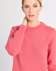 Woman wearing a pink sweater against a plain background