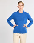 Woman wearing a blue sweater and beige pants on a white background