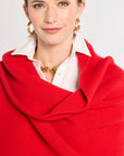 Woman wearing a red scarf over a white shirt on a plain background