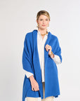 Woman wearing a blue cardigan over a white shirt on a light gray background