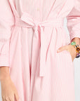 Close-up of a person wearing a pink striped dress with a belt.