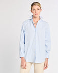 Woman wearing a light blue striped shirt against a white background