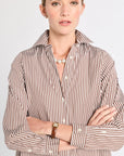 Woman wearing a brown and white striped shirt on a plain background