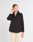 Woman wearing a black shirt and beige pants on a white background