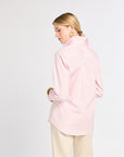 Woman wearing a light pink shirt and beige pants on a white background