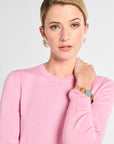 Woman wearing a pink sweater with jewelry on a white background