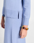 Person wearing a light blue outfit with a colorful bracelet on a white background