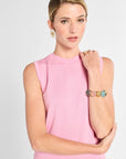 Woman wearing a pink sleeveless top with a plain background