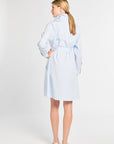 Woman wearing a light blue striped dress against a white background