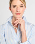 Close up picture of woman in light blue stripe shirt dress with jewelry.