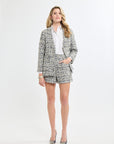 Woman wearing a tweed suit with a white shirt on a white background