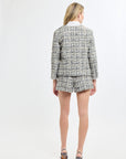 Woman wearing a tweed suit standing against a white background