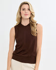 Woman wearing a brown sleeveless top and beige pants on a white background