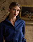 Woman modeling a navy blouse with stripes on a tan background