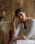 Woman modeling a white cropped cardigan in a studio setting