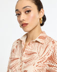 Woman wearing a patterned shirt against a plain background