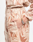 Person wearing a patterned outfit with a hand pointing to the fabric.