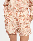 Person wearing a patterned outfit with shorts and a top on a plain background