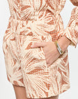 Person wearing a patterned dress with their hands in the pockets on a plain background