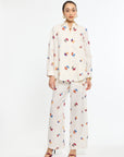 Woman wearing a cream-colored outfit with colorful floral patterns on a white background