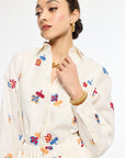 Woman wearing a white blouse with colorful butterfly patterns on a plain background