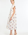 Woman wearing a white dress with colorful floral pattern on a white background