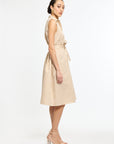 Woman wearing a beige sleeveless dress with a belt on a white background
